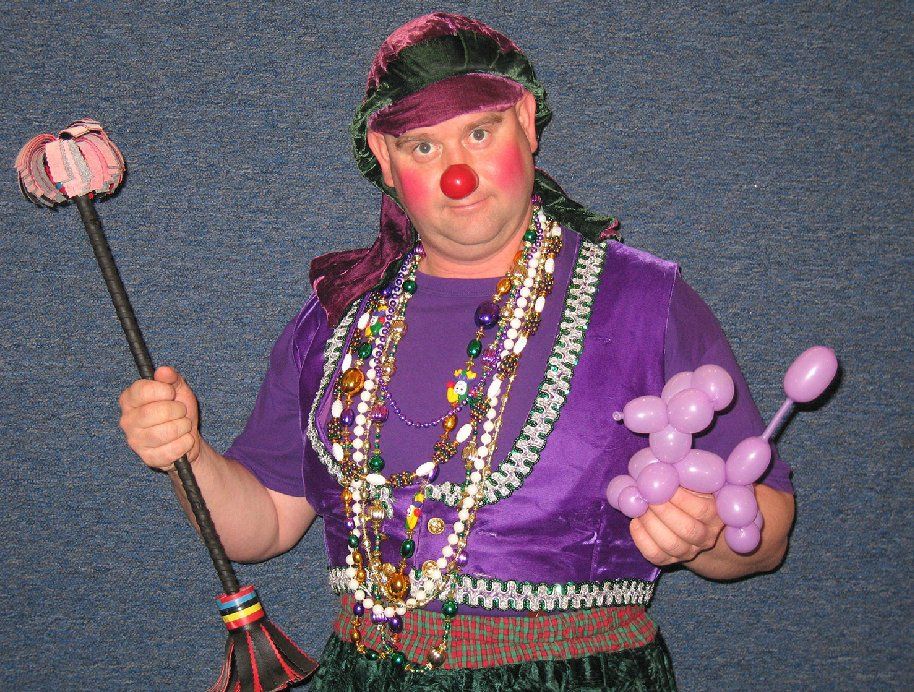 A man in a clown costume is holding balloons and a broom