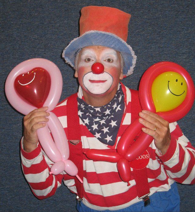 A man dressed as a clown is holding balloons in his hands