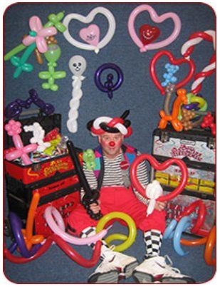 A clown is surrounded by balloons including heart shaped balloons