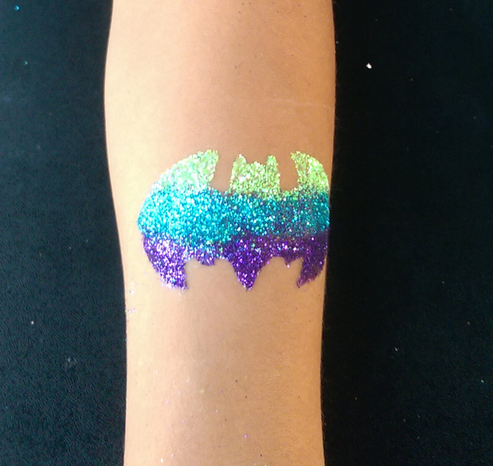 A person has a colorful batman tattoo on their arm