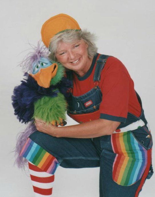 A woman in overalls is hugging a stuffed bird