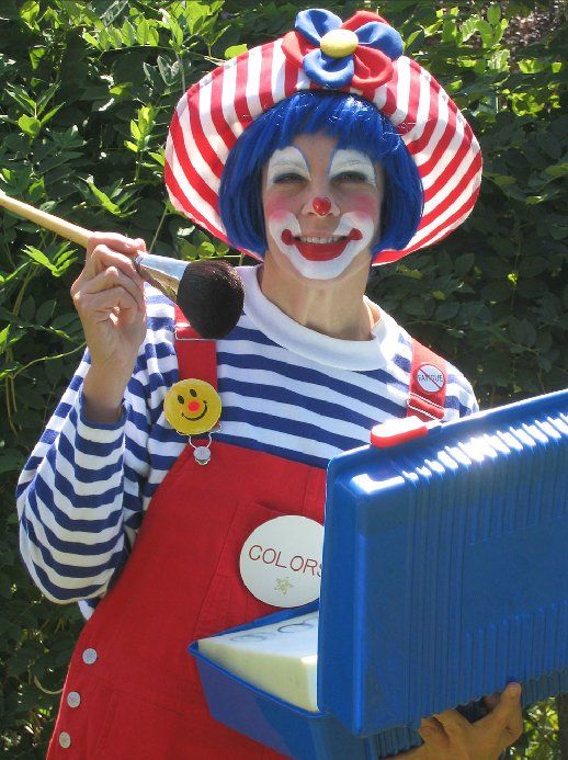 A clown is holding a brush and a box that says color