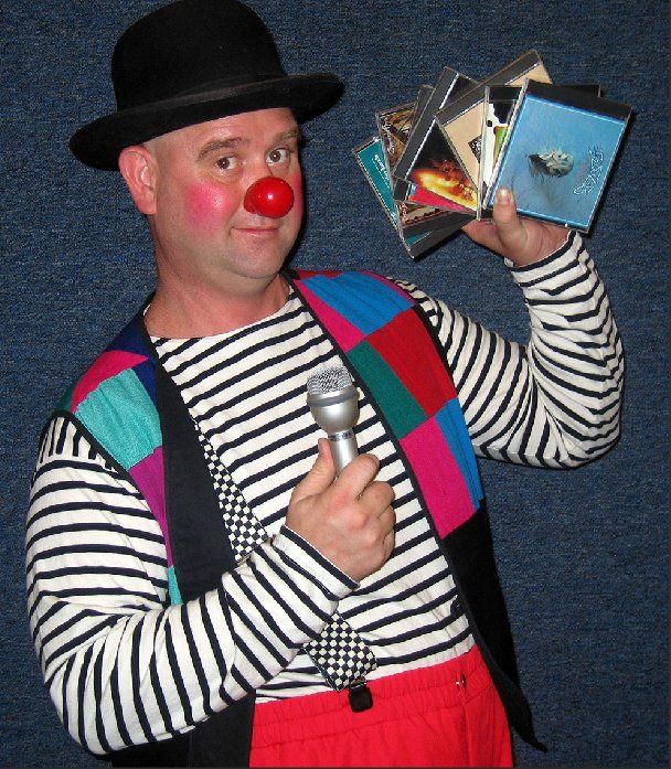 A clown is holding a microphone and a stack of cds
