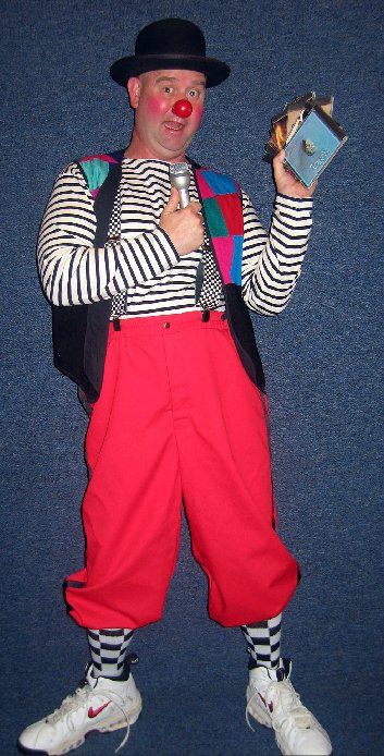 A man dressed as a clown is holding a box and a microphone