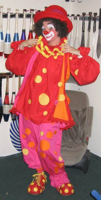 A clown is standing in front of a row of baseball bats