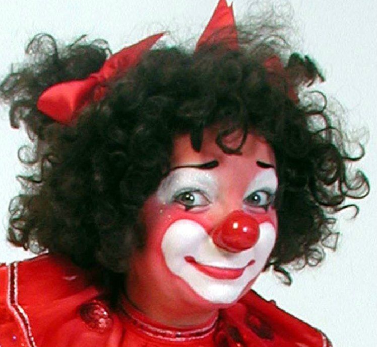 A woman dressed as a clown with a red bow in her hair