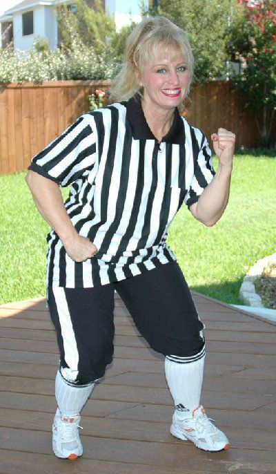 A woman in a striped referee uniform is standing on a deck.