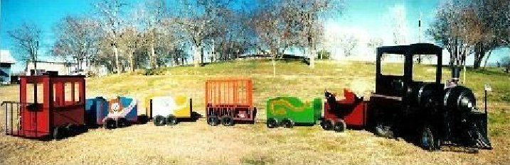 A toy train is sitting in the middle of a field.