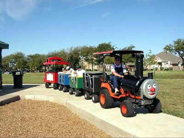 A man is driving a train made out of a lawn mower.