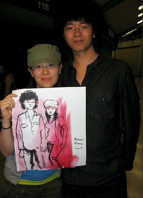 A man and a woman holding up a drawing with the number 115 in the background