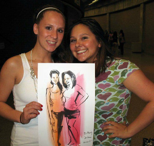 Two women standing next to each other holding a drawing of two women