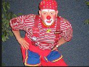 A man dressed as a clown is standing with his hands on his hips.