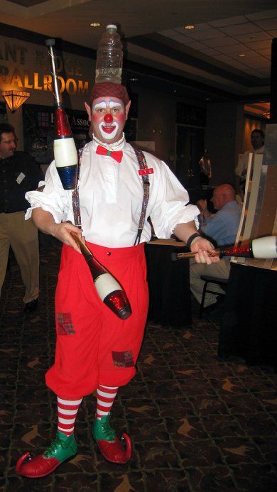 A man dressed as a clown is juggling bottles