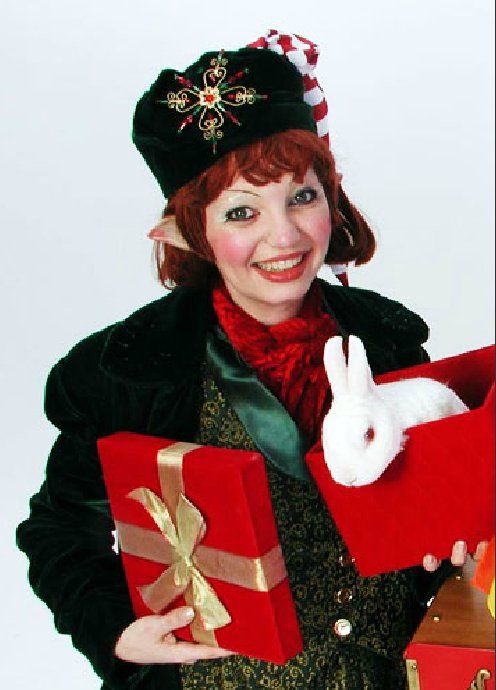 A woman dressed as an elf is holding a gift box and a stuffed rabbit