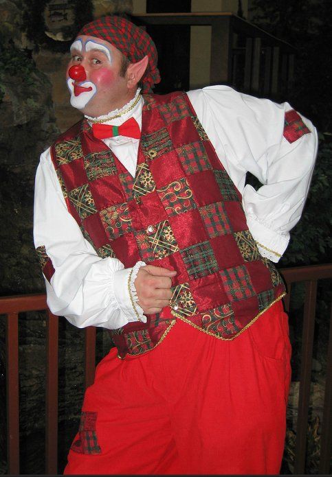 A man dressed as a clown is standing next to a railing