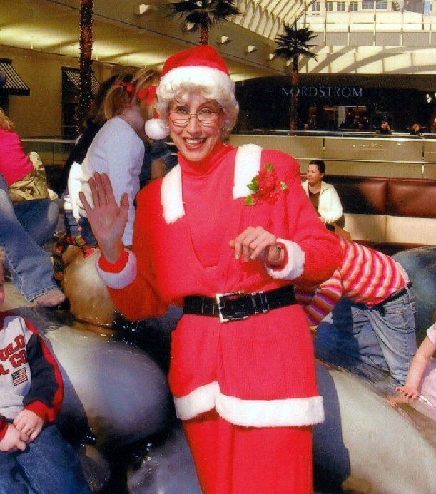 A woman dressed as santa claus is standing in front of a store called nordstrom