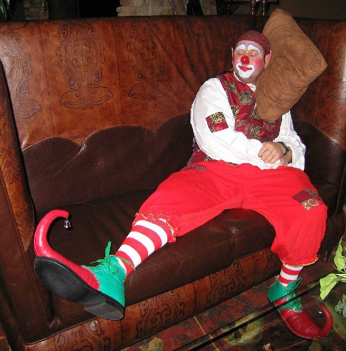 A man dressed as a clown is sitting on a couch