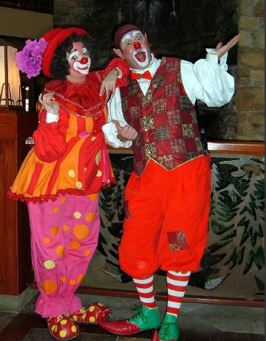 A man and a woman dressed as clowns are posing for a picture