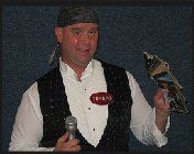 A man in a tuxedo is holding a microphone and a bird.