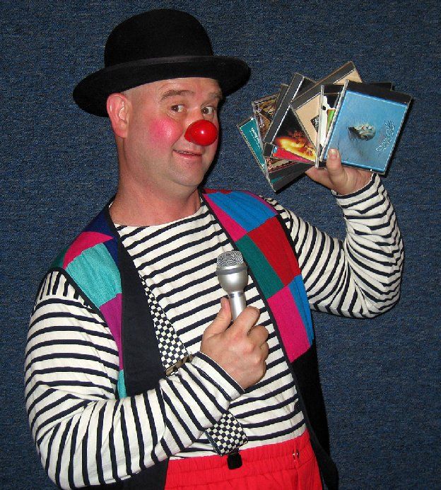 A clown holding a microphone and a stack of cds