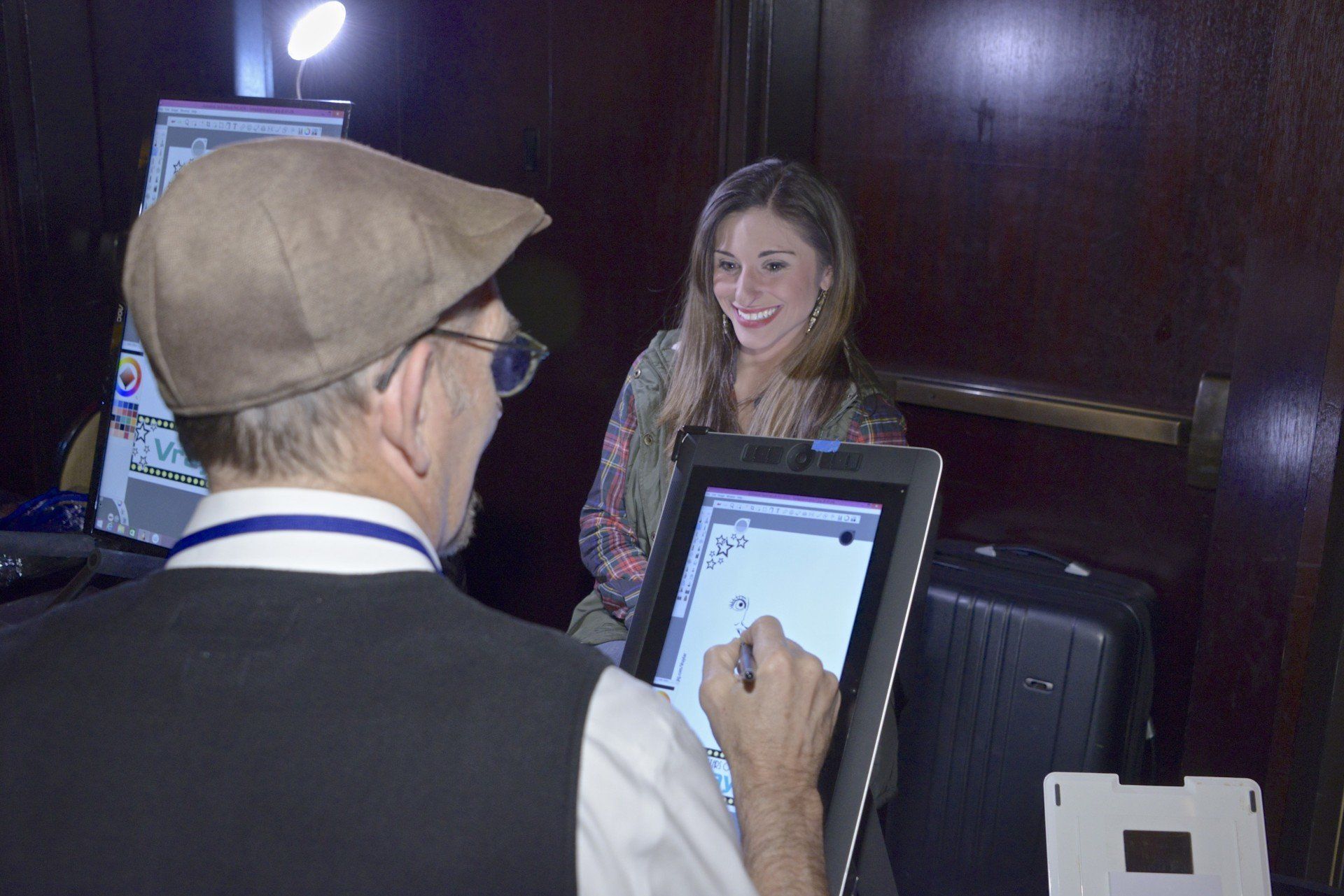 A man is drawing a picture of a woman on a tablet.