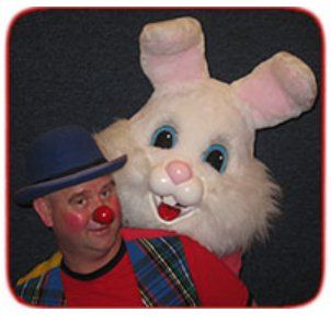 A clown with a red nose is standing next to a stuffed bunny