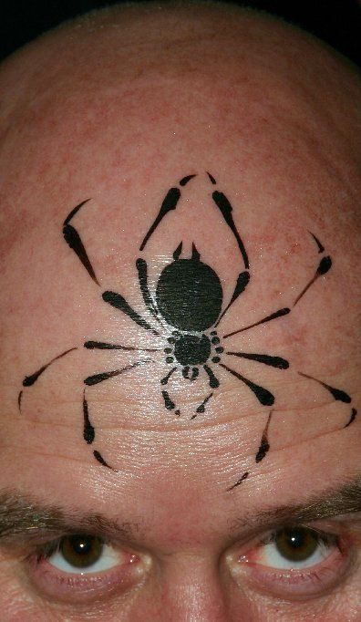 A man has a spider tattoo on his forehead.