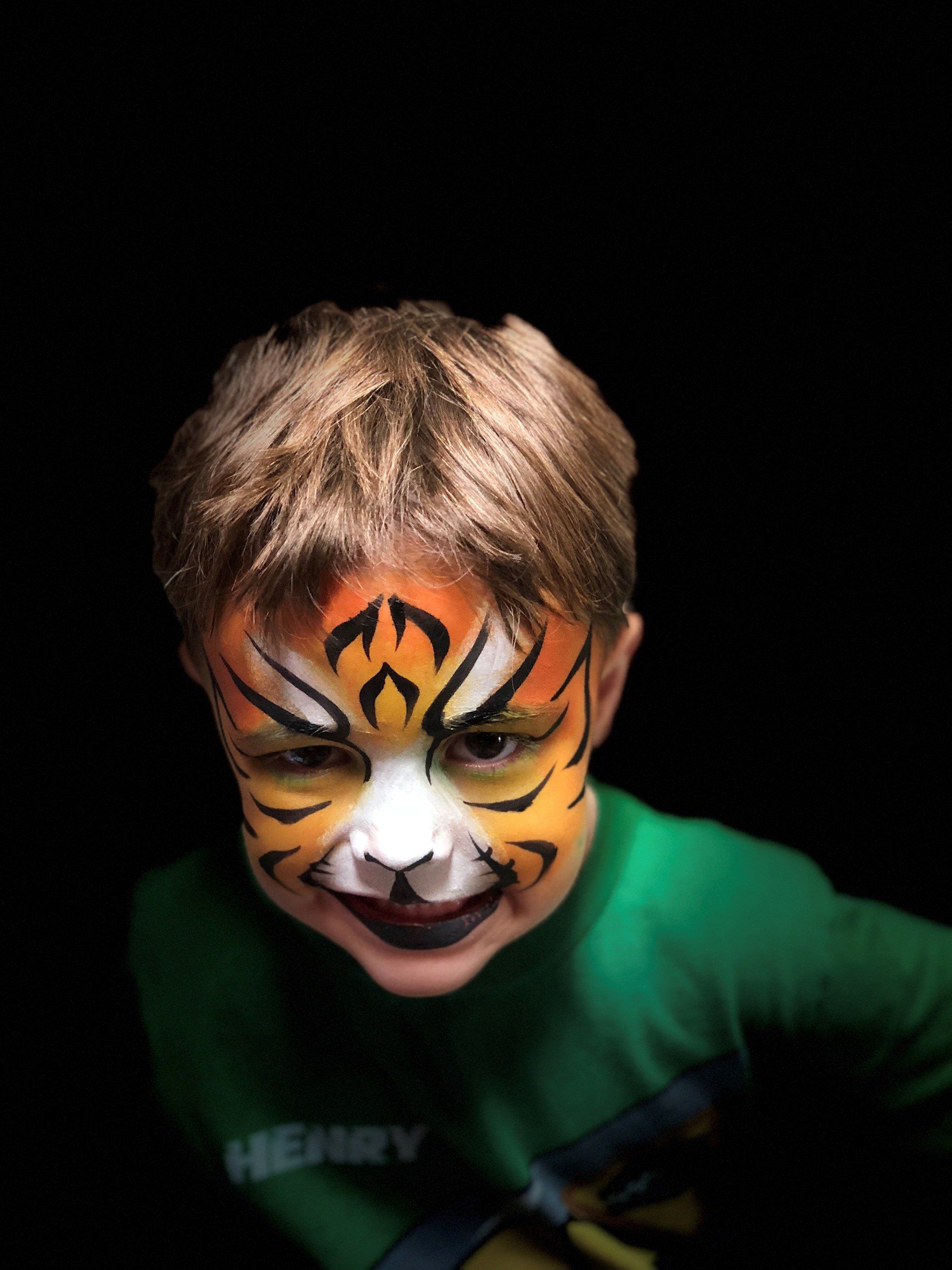 A young boy with his face painted like a tiger