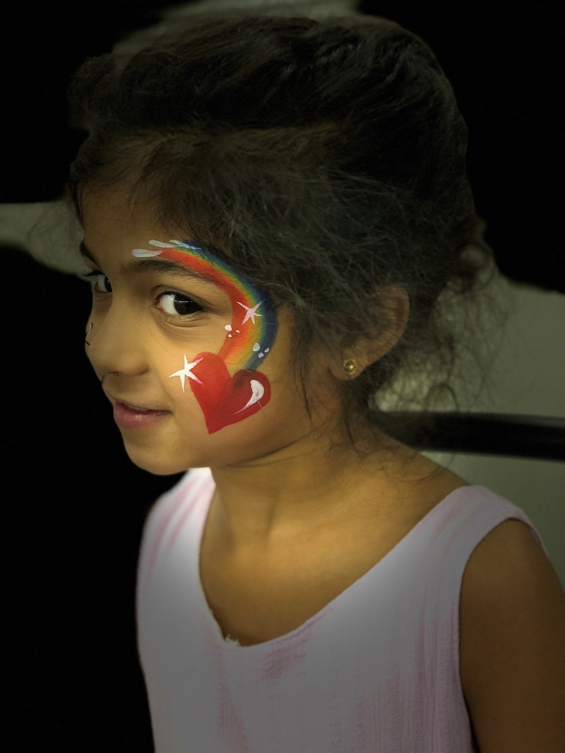 A little girl with a rainbow painted on her face