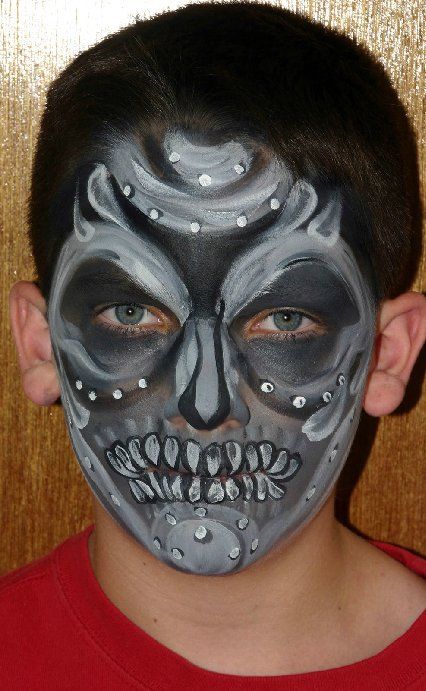 A young boy with his face painted like a skull