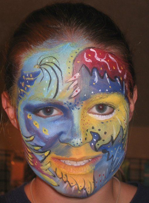 A girl has her face painted with a colorful design