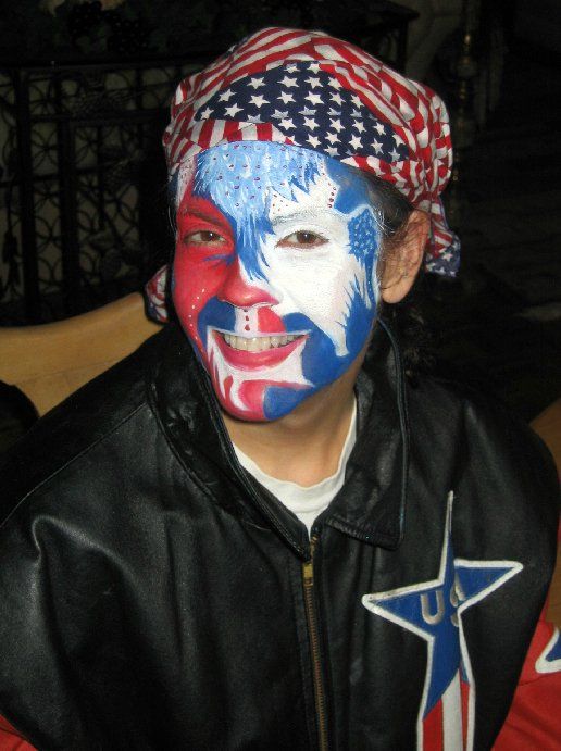 A young boy with his face painted in the colors of the american flag