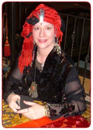 A woman wearing a red turban sits at a table