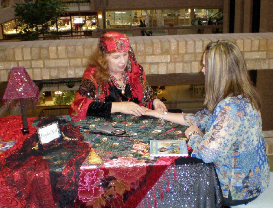 A woman is sitting at a table talking to another woman