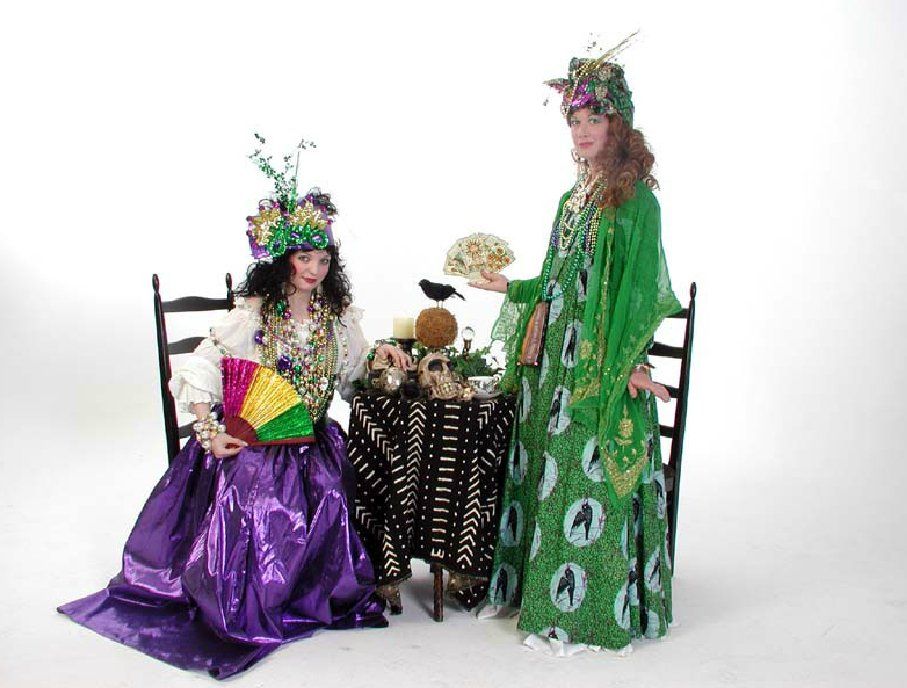 Two women in mardi gras costumes are sitting at a table