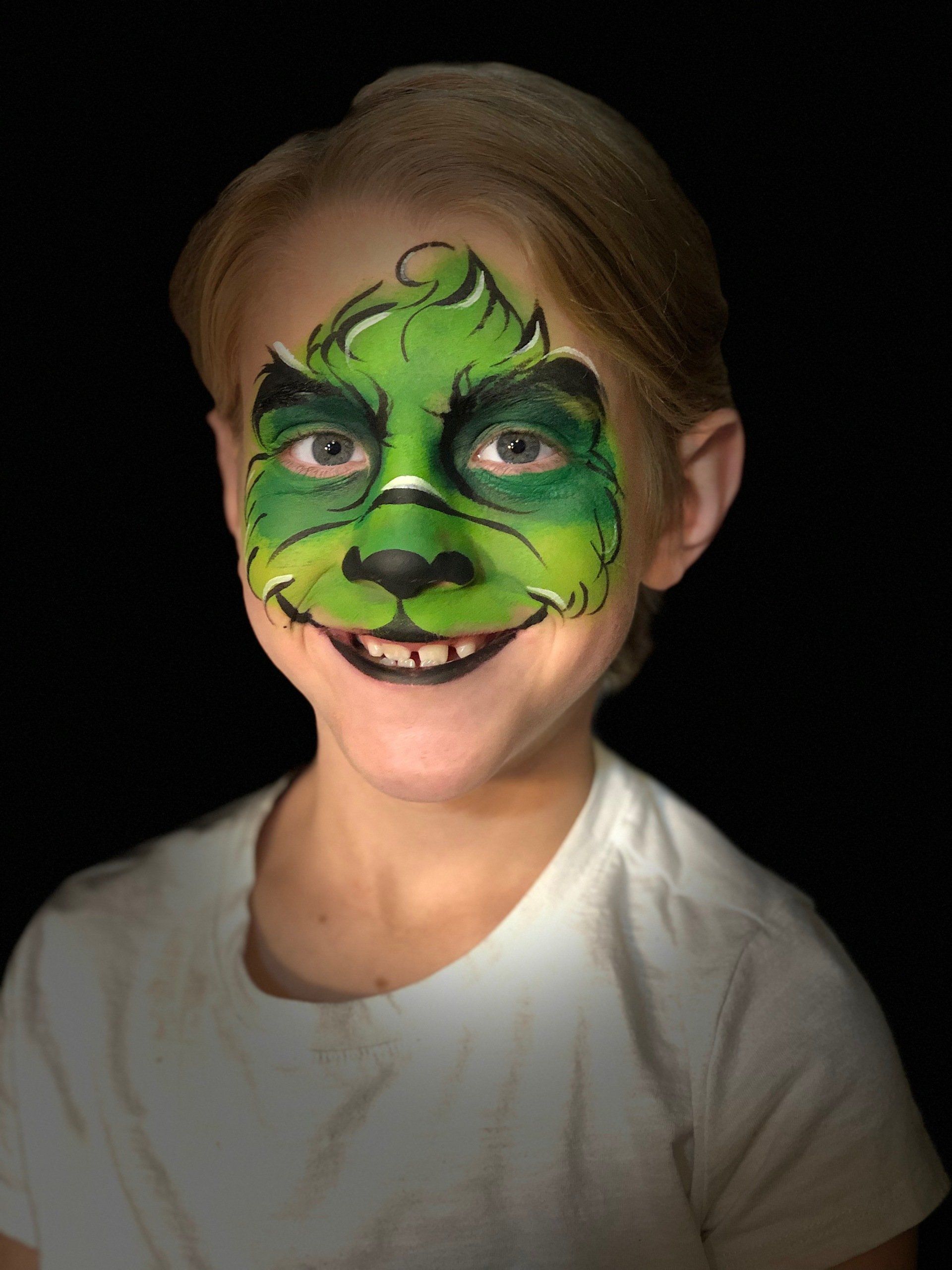 A little girl with a grinch face painted on her face