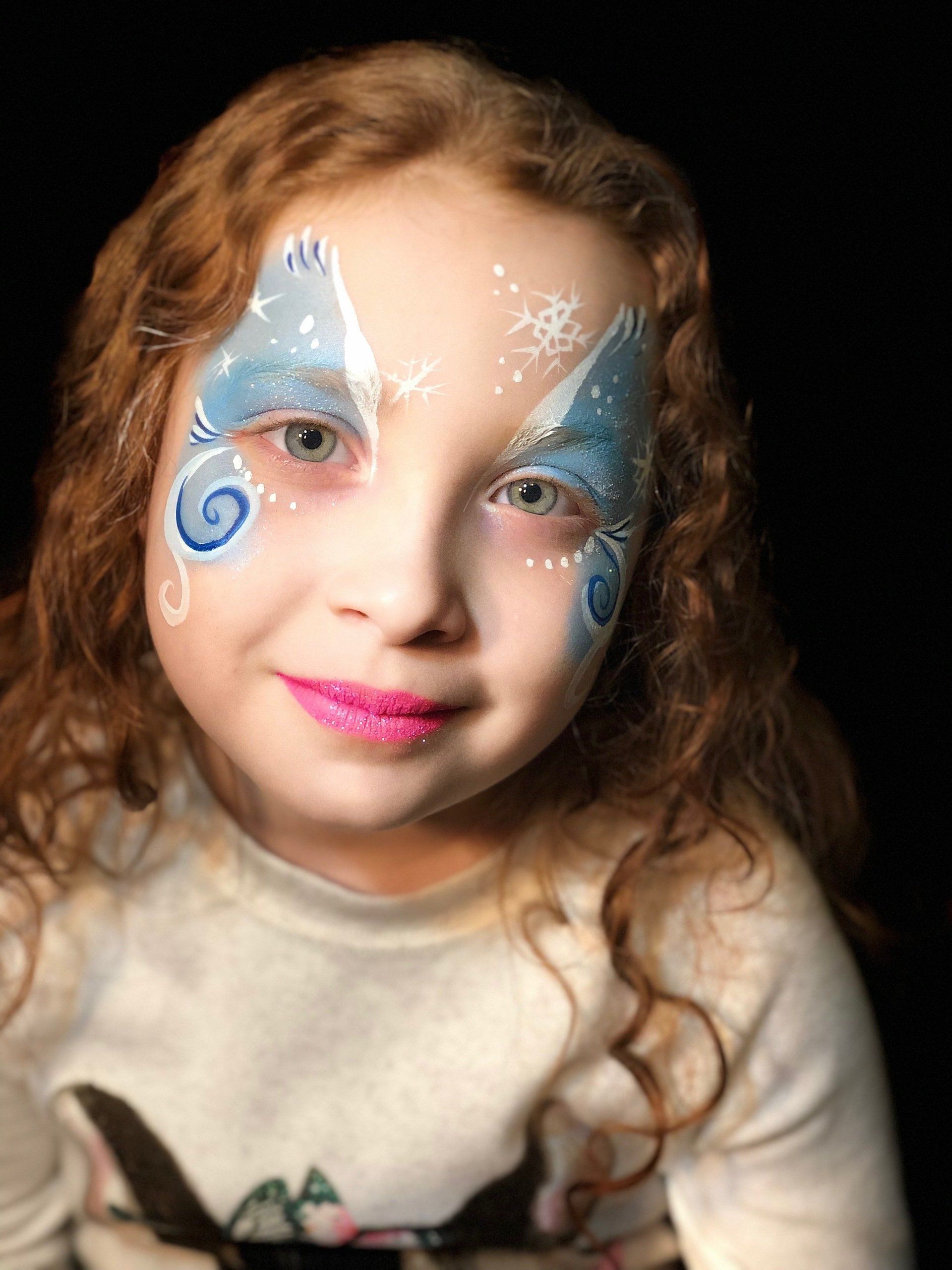 A little girl with her face painted like a butterfly.