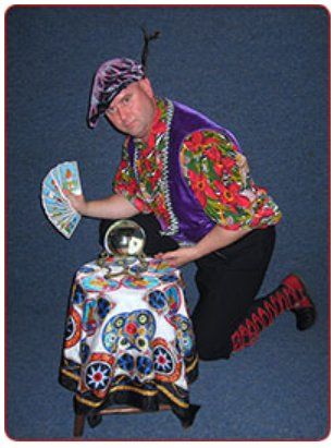 A man in a colorful outfit is holding a fan and a crystal ball