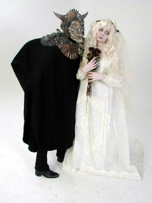A man dressed as a skeleton and a woman dressed as a bride stand next to each other