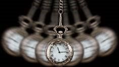 A pocket watch is hanging from a chain surrounded by other pocket watches.