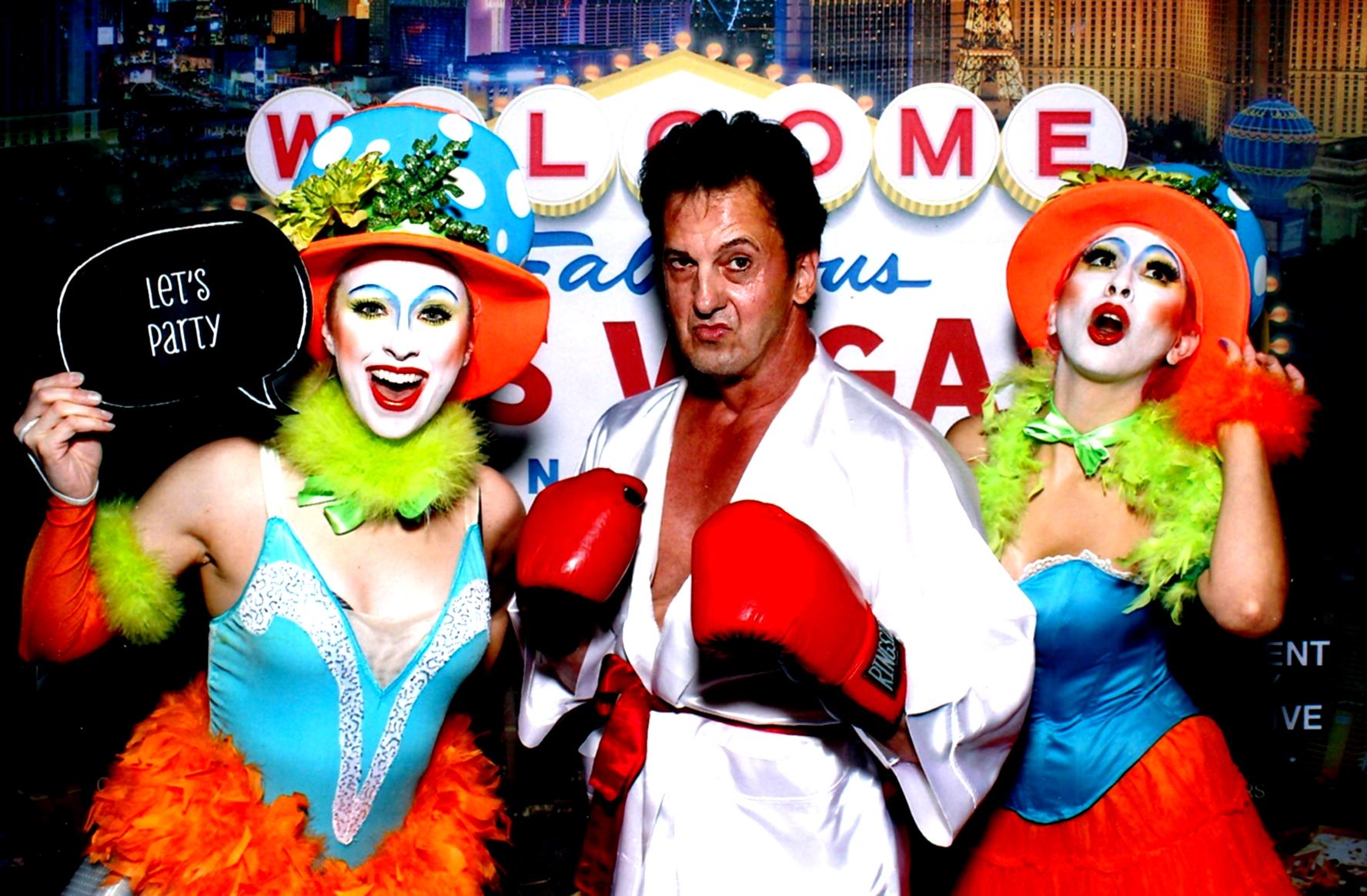 A man wearing boxing gloves poses with two women