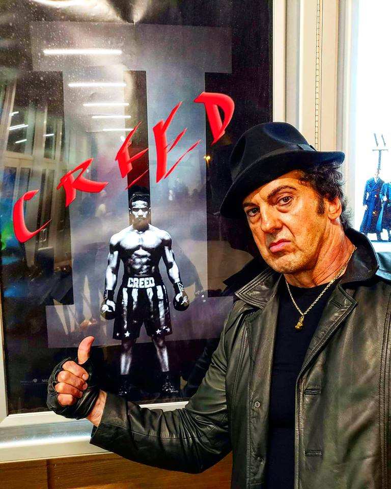 A man standing in front of a poster that says creed