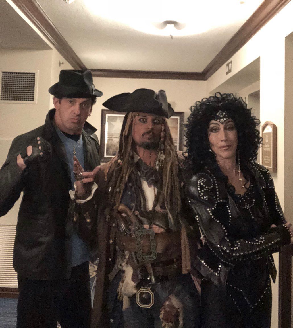 A man in a pirate costume stands between two women