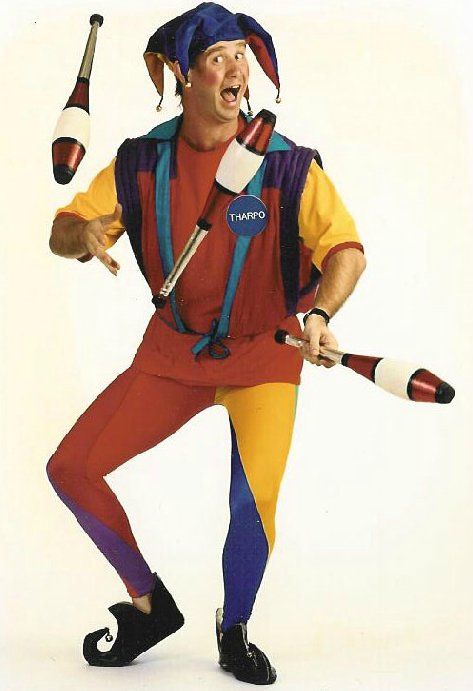 A man in a jester costume is juggling two clubs