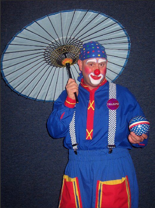 A clown holding an umbrella with the letter x on his shirt