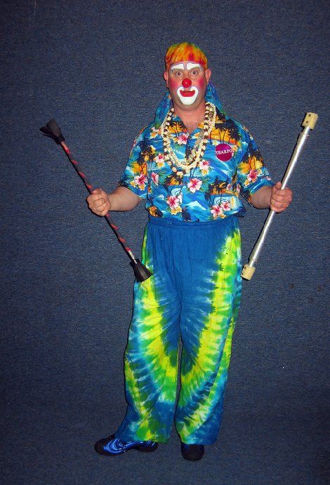 A man dressed as a clown is holding two sticks