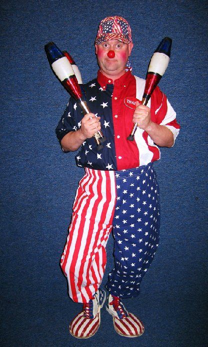 A clown in an american flag outfit holds two juggling pins