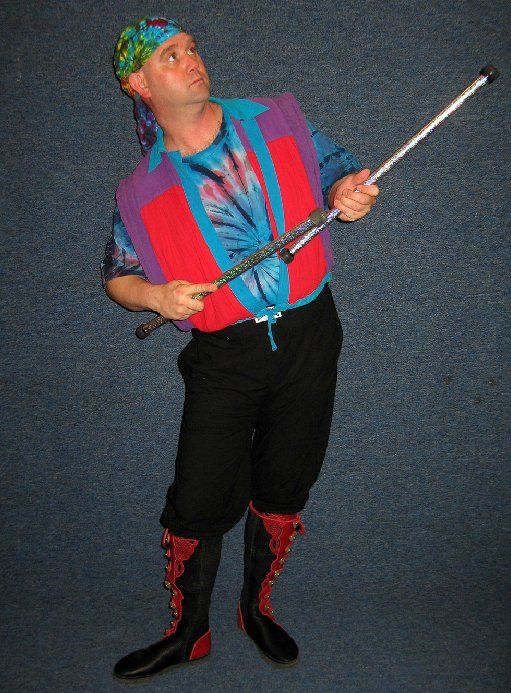 A man in a colorful outfit is holding a stick