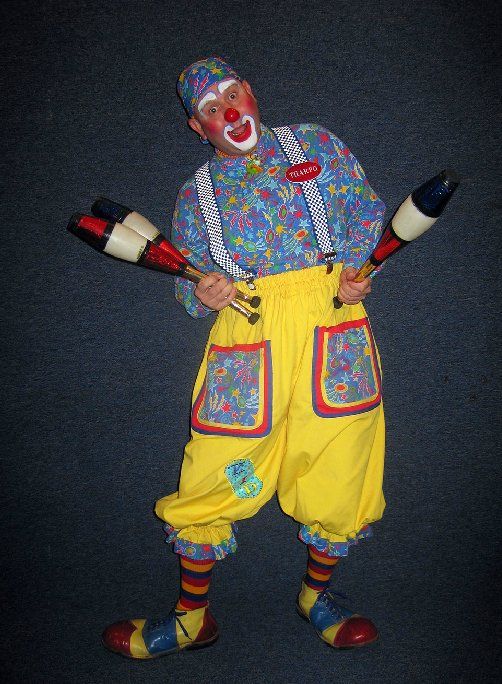 A clown is holding two juggling pins in his hands.