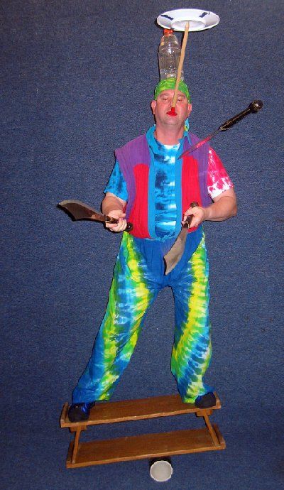 A man in a clown costume is balancing a plate on his head